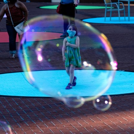 children playing with bubbles on street